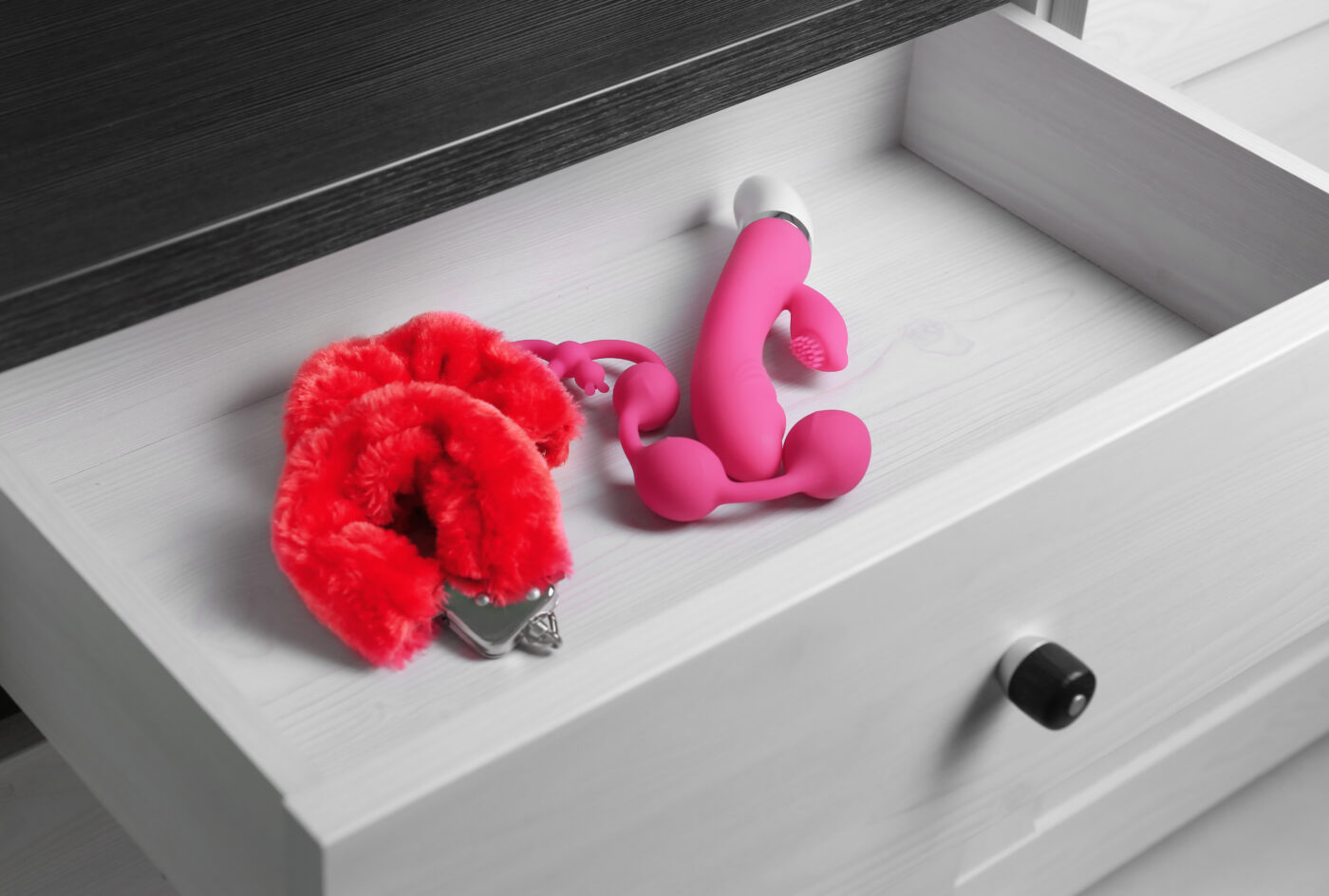 Pink toys in a drawer with red accessories.